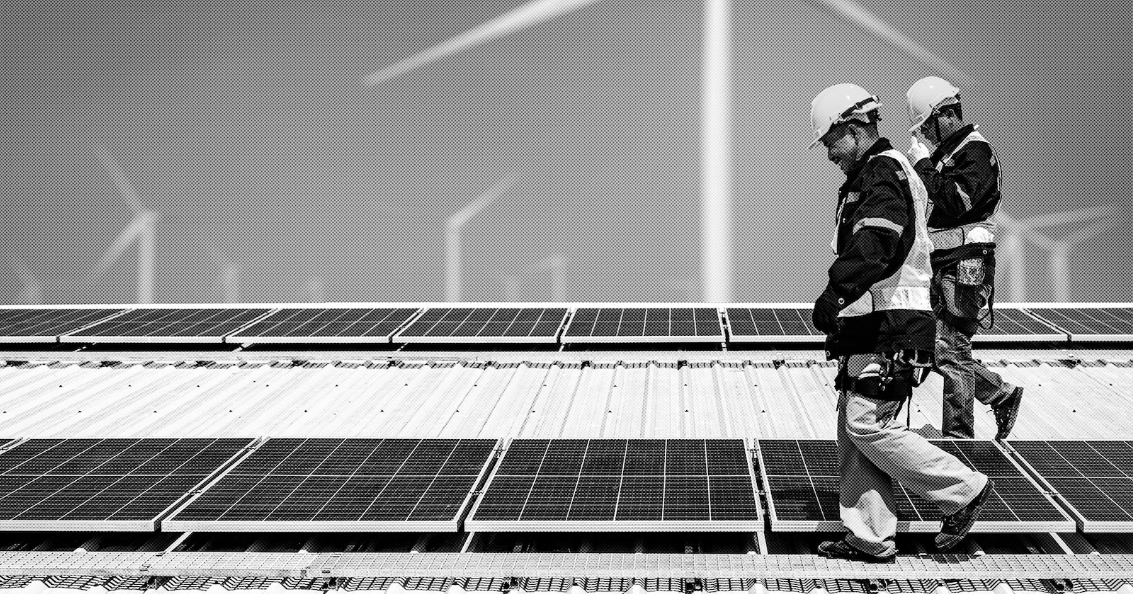 Photograph of workers inspecting solar panels with wind turbines in the distance